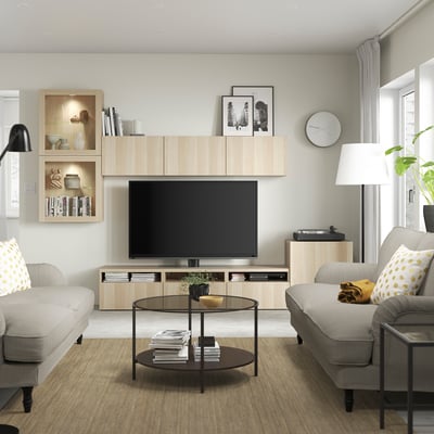 Moderne stue med BESTÅ-tv-bord, bøger, indretning, beige sofaer og pladespiller.