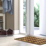 Moderne entré med BETALVÄG-måtte, geometrisk mønster, stor, næsten glasdør, røde sneakers, blå jakke.