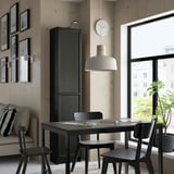 Moderne spiseplads BILLY reol i sort, stort vindue, sorte stole rundt om bordet, beige sofa med puder og vægkunst.