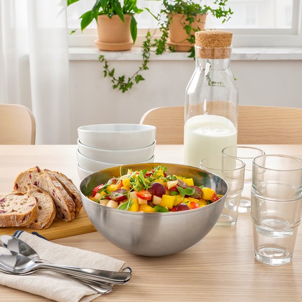 Bordsæt med rustfri stålskål med salat, brød, glas og karaffel, velegnet til forskellige anvendelser og nem at rengøre.