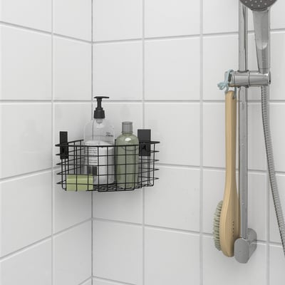 Sort trådkurv i brusebadet holder flasker, monteret nær brusehovedet.