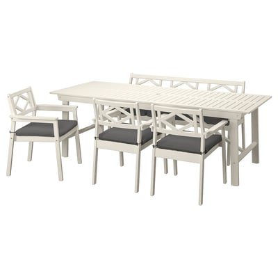 Et hvidt udendørs spisebordssæt med et rektangulært bord og syv matchende stole, seks med mørkegrå hynder.