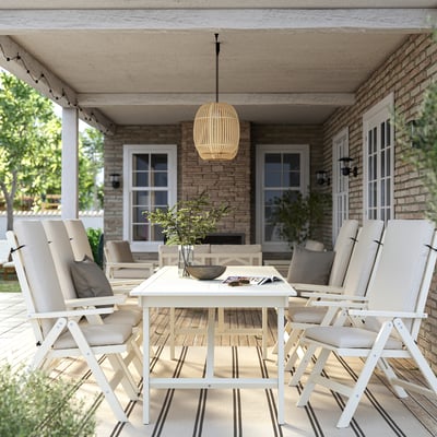 Terrasse med BONDHOLMEN akacie spisebord og stole, stribet tæppe, hængende lampe, beige puder, hyggelig atmosfære.