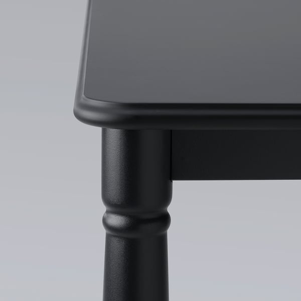 Sort rektangulært spisebord med glatte, afrundede kanter og robuste, cylindriske ben. Elegant, moderne design.