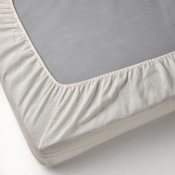 Et nærbillede af et hvidt stræklagen i 100 % hør med elastikkanter, der er designet til at passe til madrasser op til 36 cm tykke.
