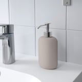 Sæbedispenser på en hvid vask, der afspejler moderne stil, passer sammen med andet tilbehør i EKOLN-serien.