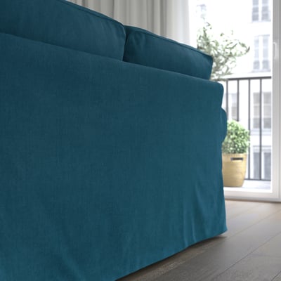 Blå sofa ved vindue, bløde hynder, aftageligt betræk.