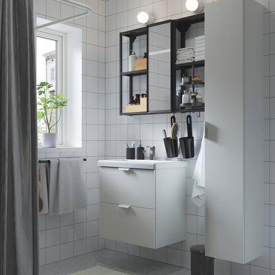 Moderne badeværelse med hvidt ENHET vaskeskab, håndvask, spejl og hylder. Minimalistisk design, belysning og organiserede håndklæder.
