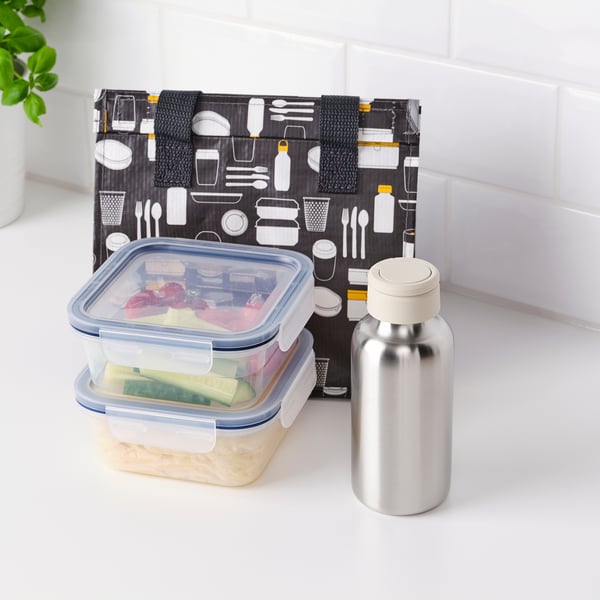 Bordplade med bento-boks og vandflaske. Bento-kassen rummer forskellige madvarer. Vandflasken er i rustfrit stål med håndtagslåg.