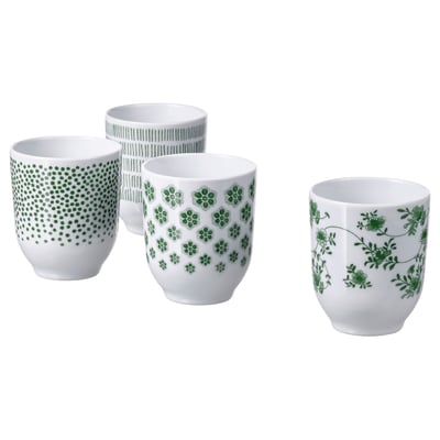Fire grønmønstrede hvide porcelænskrus med prikker, striber, blomster og bladmotiver arrangeret i en gruppe.