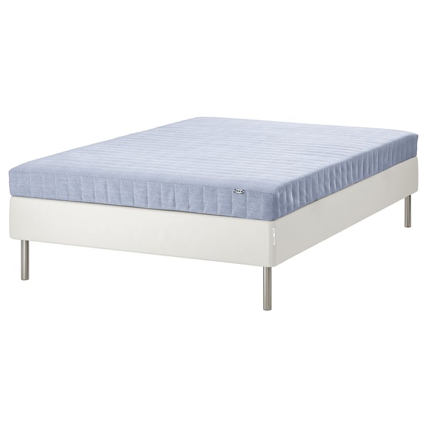 En ESPEVÄR/VADSÖ seng i hvid med en blå quiltet madras. Designet er minimalistisk med metalben.