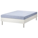 En ESPEVÄR/VADSÖ seng i hvid med en blå quiltet madras. Designet er minimalistisk med metalben.