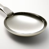 Ske i rustfrit stål med buet håndtag og dyb skål, designet til omrøring og servering, vist med en skyggefuld hvid baggrund.