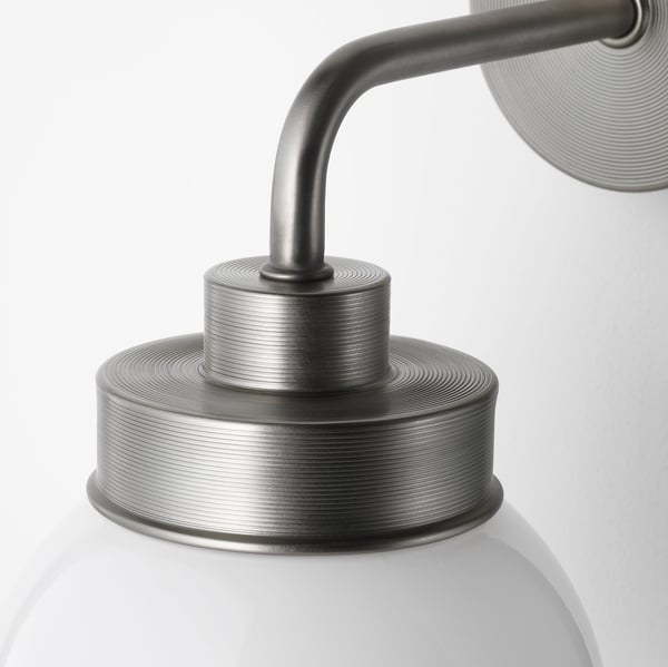 Moderne væglampe med tekstureret metalplade, buet arm og matteret glasskærm. Design af høj kvalitet, velegnet til badeværelser.