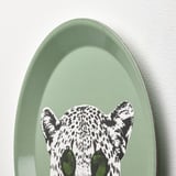 En stilfuld grøn oval vægdekoration med en legende hvid leopard med sorte pletter og grønne øjne.