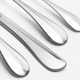 Polerede metalliske skeer arrangeret pænt, reflekterer lys, viser slankt, moderne design og skinnende, holdbar finish.