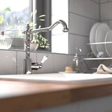 GLITTRAN krom hane i køkken, poleret messing, hvidt keramisk håndtag, moderne klassisk design; større end genstande i nærheden.