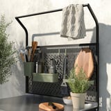 Moderne sort metal køkkengitter med hængende redskaber, håndklæde og planter.
