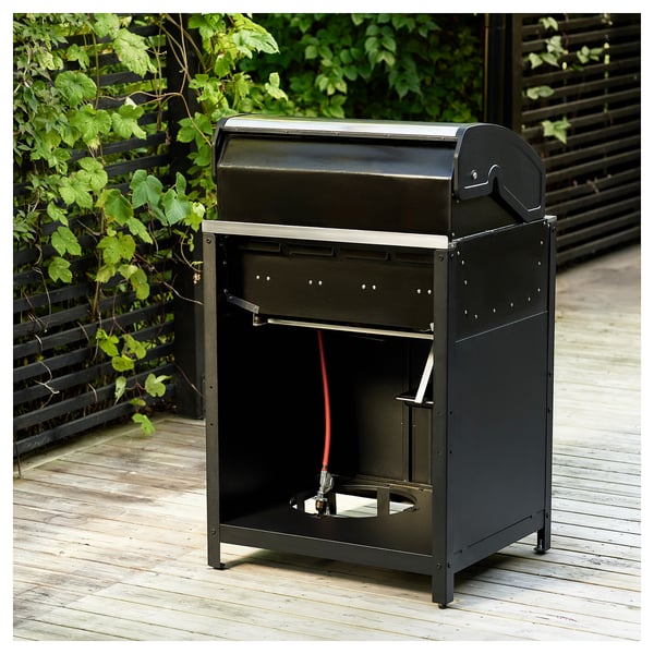 Sort GRILLSKÄR gasgrill på trædæk med fire brændere, rustfrit stål og emaljehus, stort kogeområde og indbygget termometer.