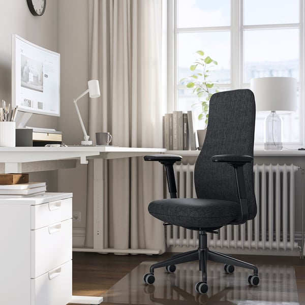 Hjemmekontor med GRÖNFJÄLL mørkegrå ergonomisk stol, hvidt skrivebord og computer. Stolen passer pænt under skrivebordet, med justerbar for komfort.