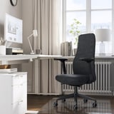 Hjemmekontor med GRÖNFJÄLL mørkegrå ergonomisk stol, hvidt skrivebord og computer. Stolen passer pænt under skrivebordet, med justerbar for komfort.
