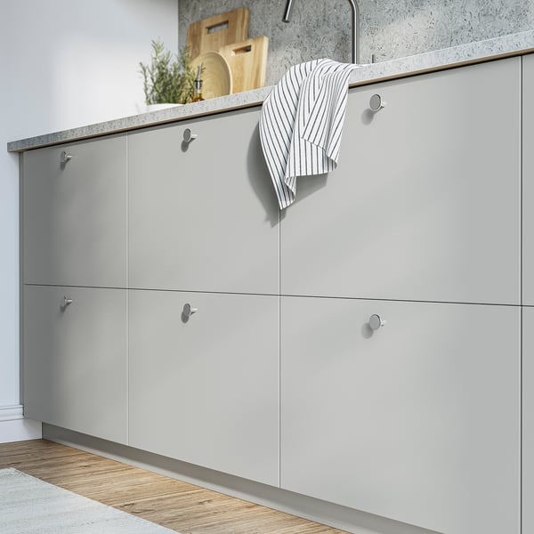 Moderne køkken med grå skabe, kromgreb og minimalistisk design. Store skabe, stribet håndklæde og træplader på bordpladen.
