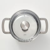 Sølvgryde med glaslåg og to sidehåndtag, designet til holdbarhed og nem hældning.
