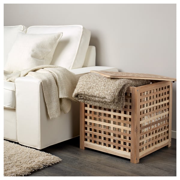 HOL sidebord i træ med gitterdesign ved siden af hvid sofa, ideel til opbevaring af tæpper.