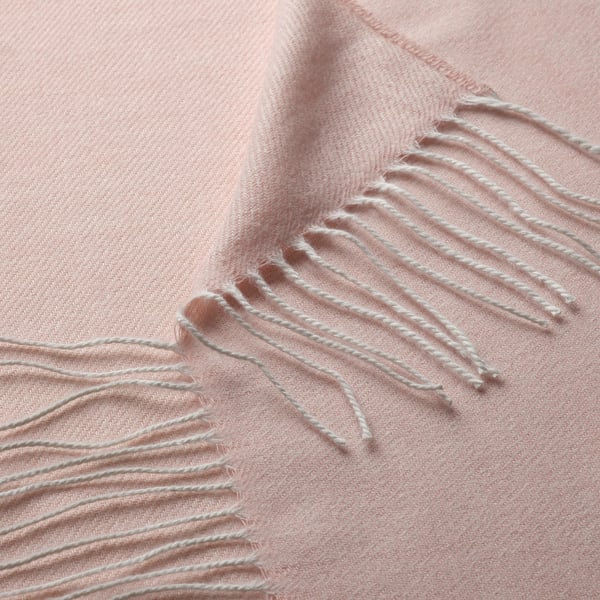 Blødt, lyserødt tæppe med delikate frynser, fremstillet af genanvendt polyester.