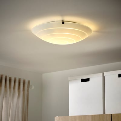 En blødt oplyst, matteret glasloftslampe hænger fra et råhvidt loft, lysstyrken er jævnt spredt for rumbelysning.