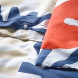 Nærbillede af dynebetræk med trykknaplukning, der viser blåt, hvidt og orange mønster.