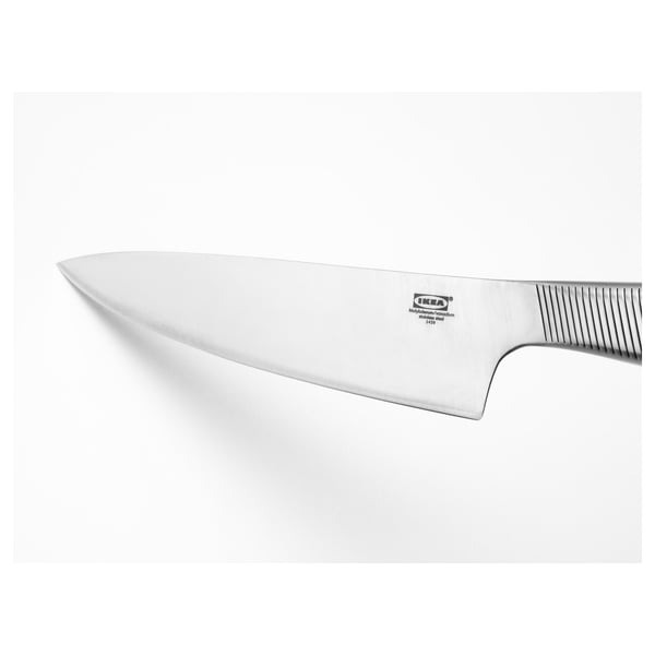 Skarpt vinklet ikea-kniv, blad i rustfrit stål med riller til greb, der hviler på en almindelig hvid baggrund.