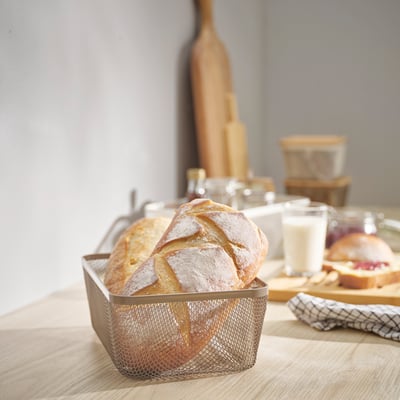 IKEA 365+ madkurv i mesh har plads til brød, der er mindre end glas, på træbordet.