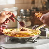 Person smører marmelade på en pandekage oven på en IKEA 365+ pande på et komfur. Pandens non-stick overflade sikrer nem håndtering af fødevarer.