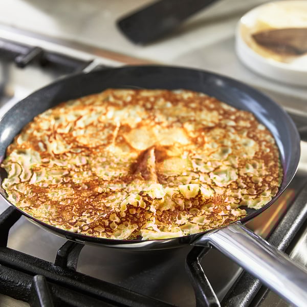 En pandekage kogt i en non-stick pande på en komfur.