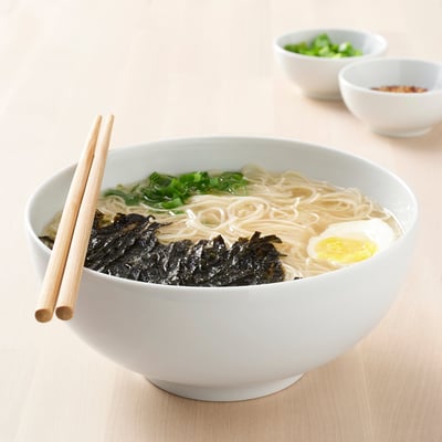 Skål med ramen nudler med toppings, klar til at spise. Spisepinde på siden.