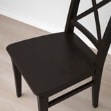 Mørk træstol med slank finish på lyst gulv, høj ryg med indviklet design.