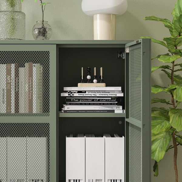 Grønt IVAR netskab, der rummer bøger og mapper. En hvid lampe sidder ovenpå med planter ved siden af og over skabet.