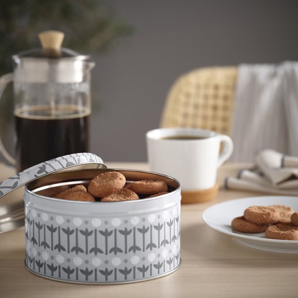En dåse med KAFFEREP-småkager, der åbnes og afslører sprøde ingefærkager. Ved siden af en kaffekop og en stempelkande med kaffe.