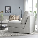 Moderne stue med KIVIK sovesofa ved stort vindue. Grå polstring, pyntepuder, sidebord med tulipaner og gulvlampe.