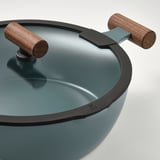 Nærbillede af en sauterpande af høj kvalitet med træhåndtag og glaslåg, der viser dens robuste konstruktion og slanke design.
