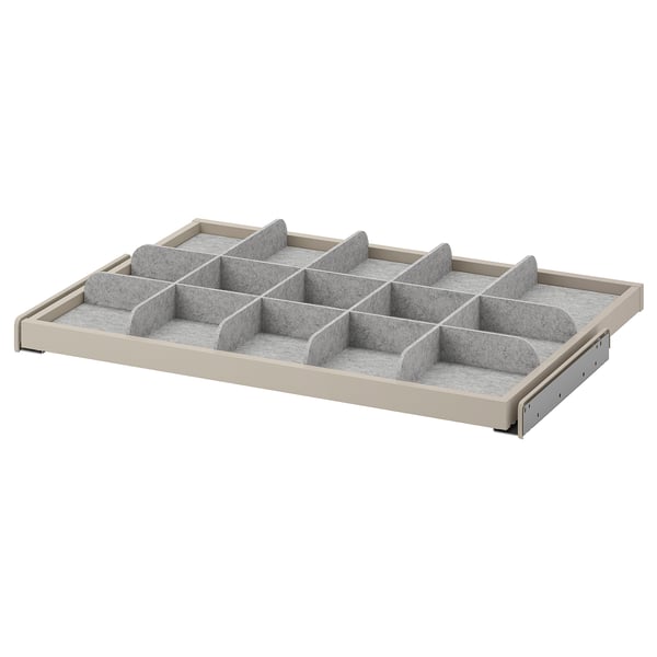 En KOMPLEMENT-beiget organiseringsbakke med flere grå rum til opbevaring. Det er et udtrukkeligt design for nem adgang.