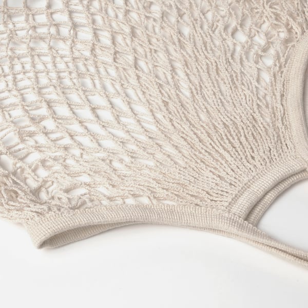 Nærbillede af vævet beige bomuldspose, der viser indviklede diamantmønstre og robust konstruktion.