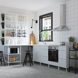 Moderne hvidt køkken med blanke fliser, hvide skabe, indbygget ovn og mikroovn. Sorte taburetter og inventar. Vindue over vasken.