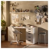 Hyggeligt hjemmekontor med hvidt LAGKAPTEN skrivebord, hylder og stol. Dekoreret med planter, kunst og inspirationstavler.