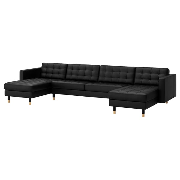 Sort l-formet lædersofa, moderne, tuftede hynder, træfødder.