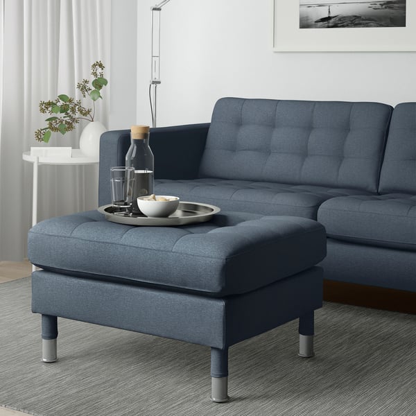 Stue med blå LANDSKRONA fodskammel og sofa, bakke, skål, drikkevarer, plante.
