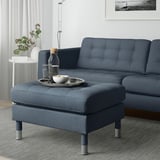 Stue med blå LANDSKRONA fodskammel og sofa, bakke, skål, drikkevarer, plante.