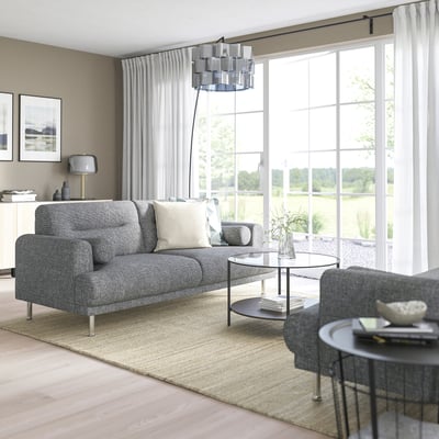Moderne stue med LÅNGARYD grå sofa, slankt glasbord og store vinduer; minimalistisk indretning.