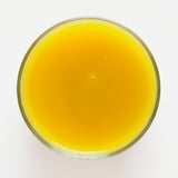 En klar, rund glasskål fyldt med en levende orange-gul smoothie lavet af mango, græskar og æble, der viser en glat tekstur.